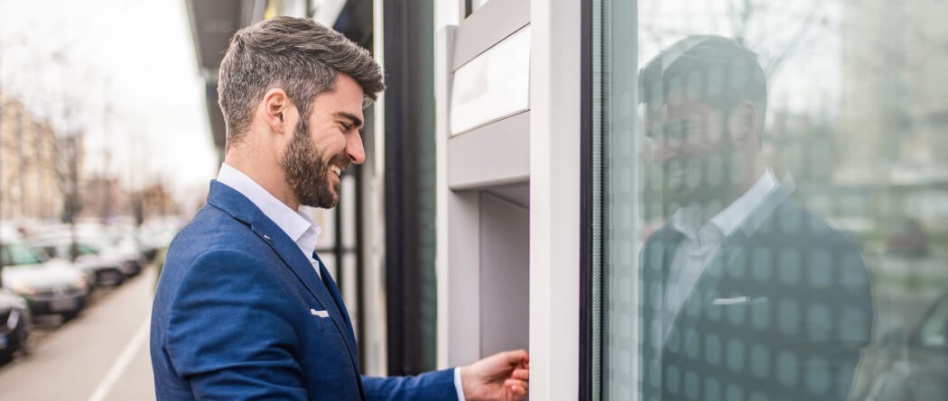 Man dressed in a business suit using an outdoor atm