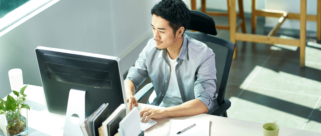 Young man working in a modern office looking at a computer monitor